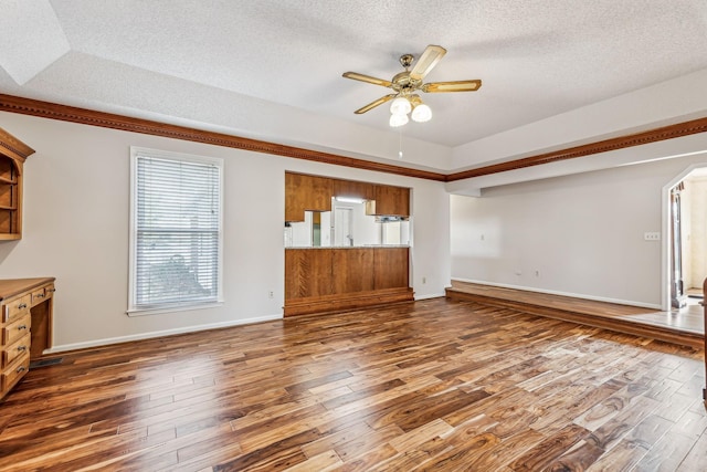 unfurnished living room with a raised ceiling, a textured ceiling, dark hardwood / wood-style floors, and ceiling fan