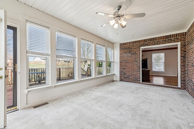 unfurnished sunroom featuring ceiling fan and a wealth of natural light