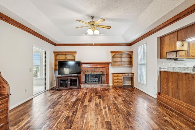 unfurnished living room featuring a fireplace, dark hardwood / wood-style floors, a raised ceiling, and a textured ceiling