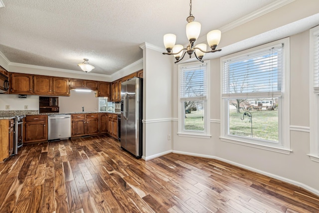 kitchen with pendant lighting, crown molding, dark hardwood / wood-style floors, and appliances with stainless steel finishes