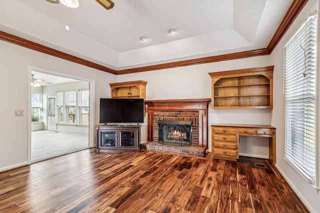 unfurnished living room featuring ceiling fan, dark hardwood / wood-style flooring, a raised ceiling, and a textured ceiling