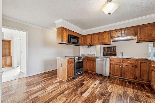 kitchen with ornamental molding, appliances with stainless steel finishes, dark hardwood / wood-style floors, and light stone countertops