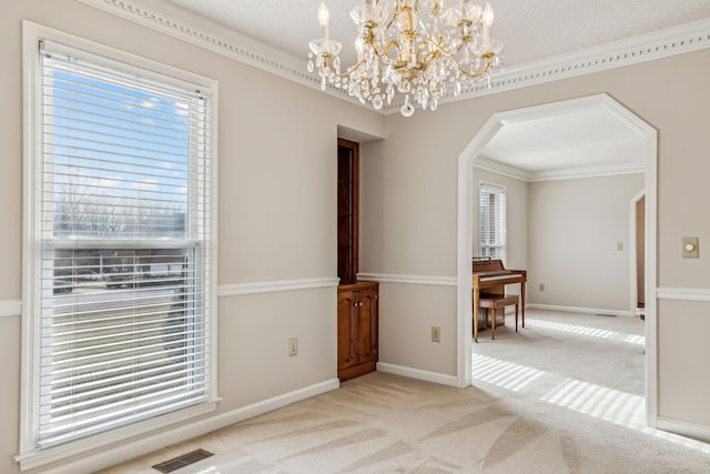 spare room with ornamental molding, a chandelier, light carpet, and a textured ceiling