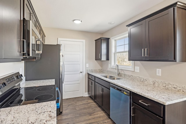 kitchen featuring dark wood-type flooring, sink, dark brown cabinets, stainless steel appliances, and light stone countertops