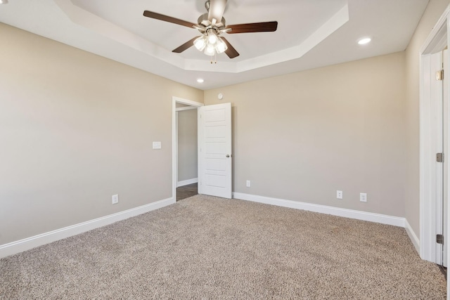 unfurnished bedroom featuring ceiling fan, a raised ceiling, and carpet