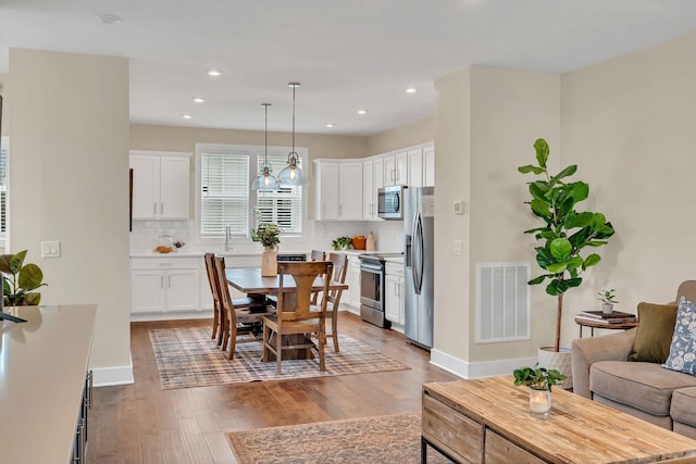 interior space featuring white cabinetry, decorative light fixtures, dark wood-type flooring, and stainless steel appliances