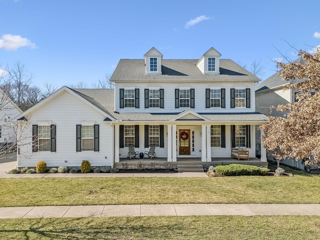 colonial-style house featuring a porch and a front yard