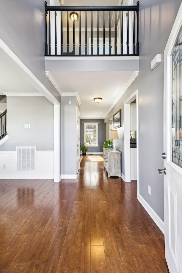 entrance foyer featuring crown molding, dark wood-type flooring, and a towering ceiling