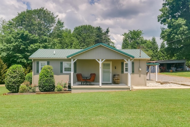 rear view of house featuring a yard and covered porch