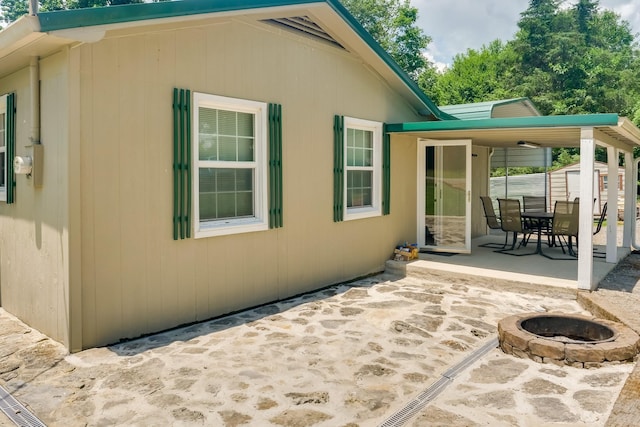 view of side of home featuring a storage unit, an outdoor fire pit, and a patio area