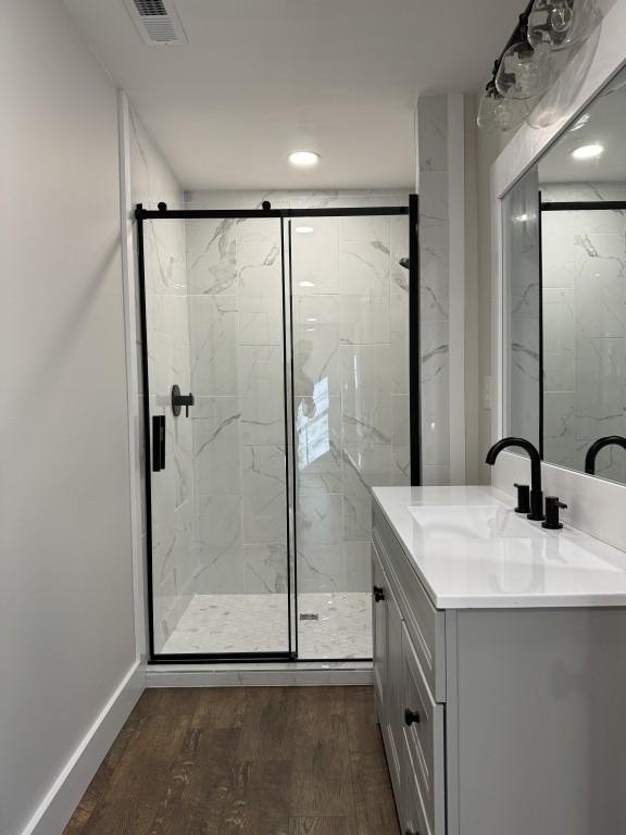 bathroom featuring vanity, hardwood / wood-style floors, and a shower with shower door