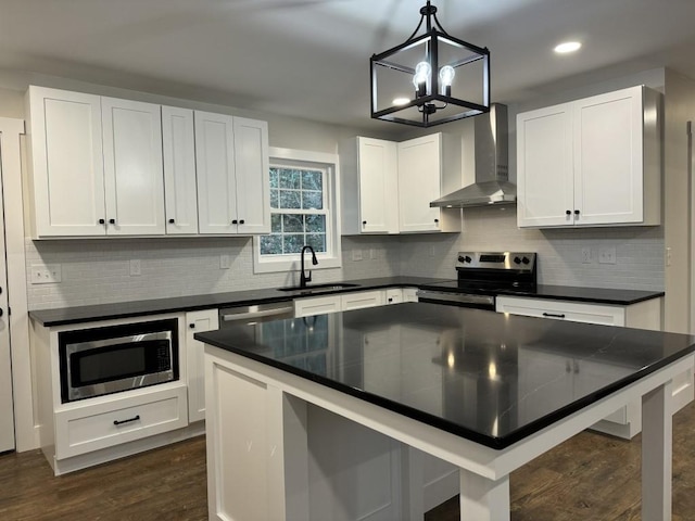 kitchen featuring white cabinetry, sink, hanging light fixtures, stainless steel appliances, and wall chimney exhaust hood