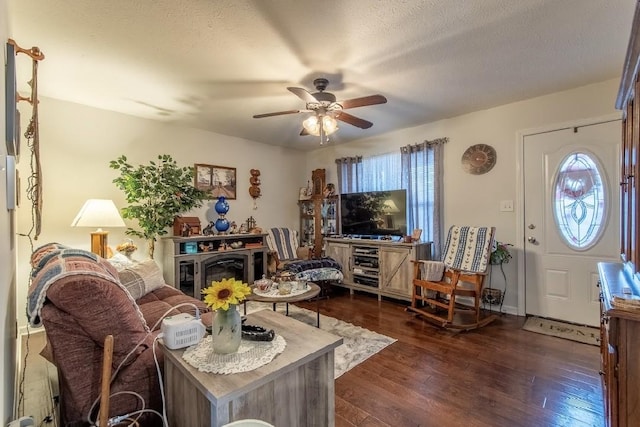 living room with ceiling fan, dark hardwood / wood-style floors, and a textured ceiling