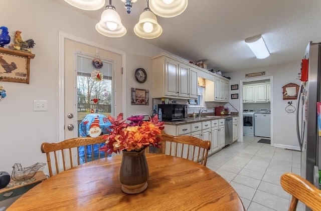 tiled dining space with a chandelier, separate washer and dryer, sink, and a textured ceiling