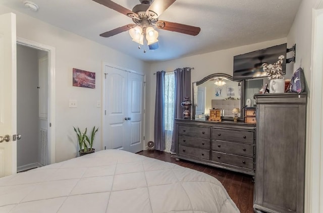 bedroom with dark wood-type flooring, ceiling fan, and a closet