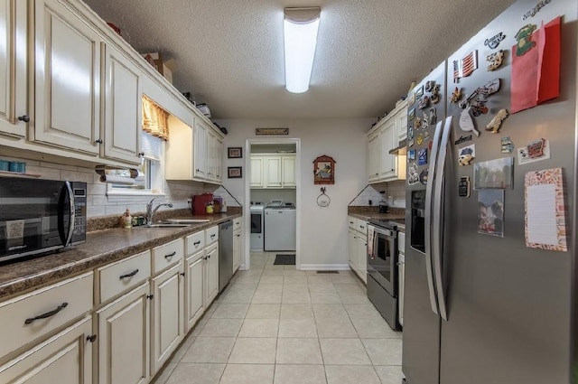 kitchen featuring light tile patterned flooring, sink, separate washer and dryer, a textured ceiling, and stainless steel appliances