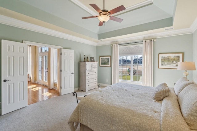 carpeted bedroom with crown molding, ceiling fan, and a tray ceiling