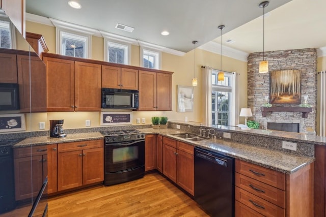 kitchen featuring sink, hanging light fixtures, ornamental molding, black appliances, and dark stone counters