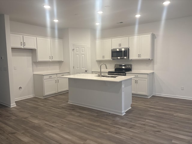 kitchen featuring dark wood-type flooring, sink, white cabinetry, an island with sink, and stainless steel appliances