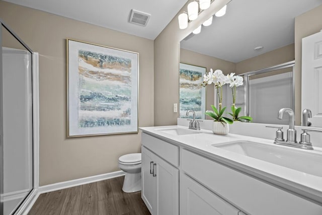 bathroom with a shower with door, vanity, hardwood / wood-style floors, and toilet