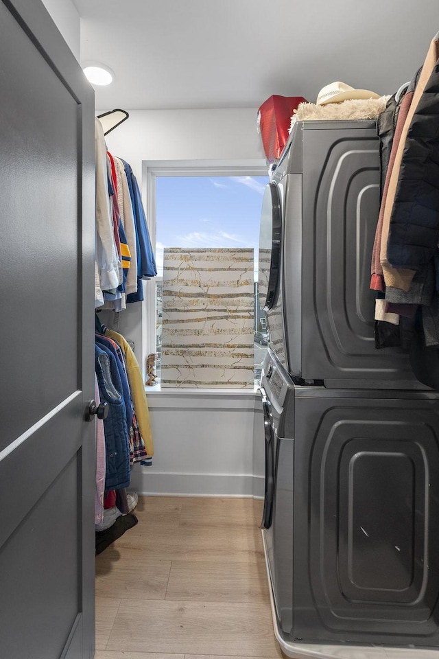 laundry area with stacked washer / drying machine and light hardwood / wood-style floors