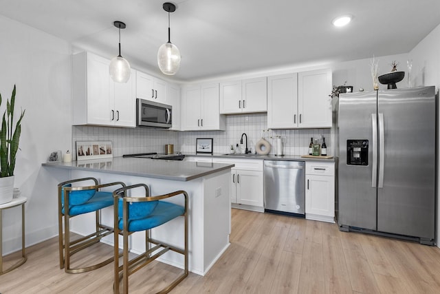 kitchen featuring white cabinetry, appliances with stainless steel finishes, kitchen peninsula, and hanging light fixtures