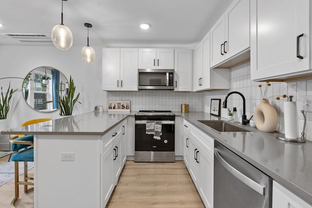 kitchen with sink, white cabinetry, pendant lighting, stainless steel appliances, and decorative backsplash