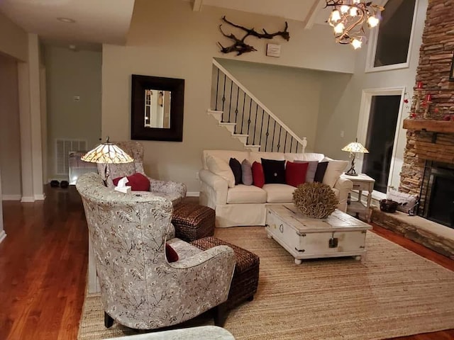 living area with a fireplace, wood finished floors, visible vents, baseboards, and stairway