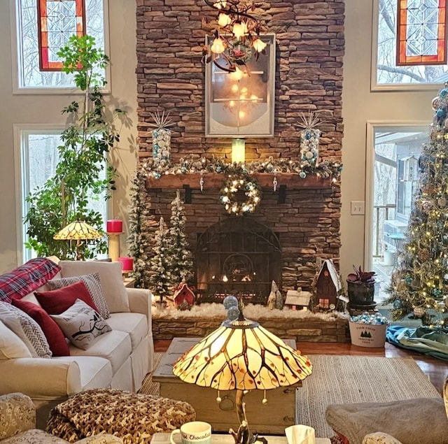 living area with a stone fireplace, wood finished floors, and a towering ceiling