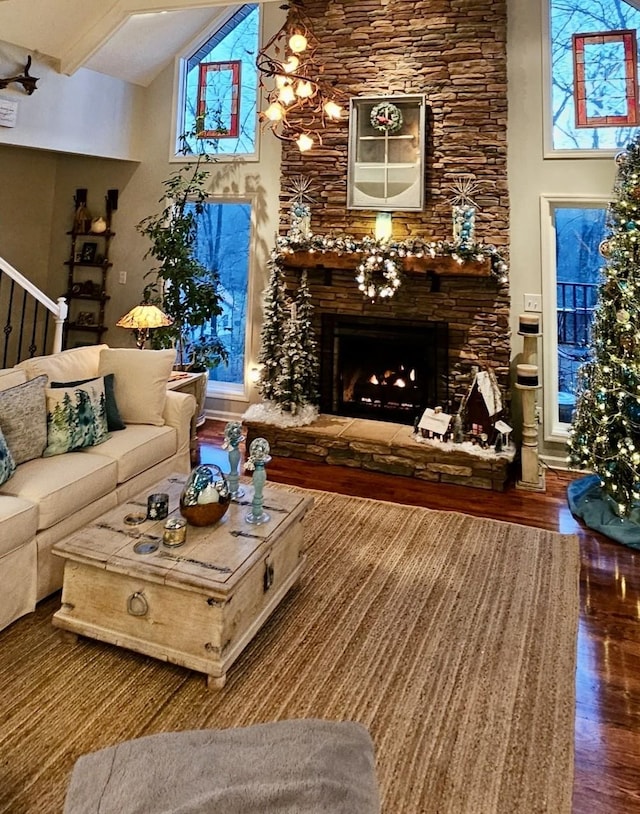 living area with high vaulted ceiling, a fireplace, wood finished floors, stairway, and beamed ceiling