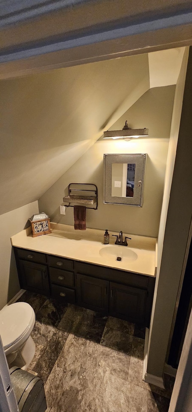 bathroom with toilet, lofted ceiling, and vanity