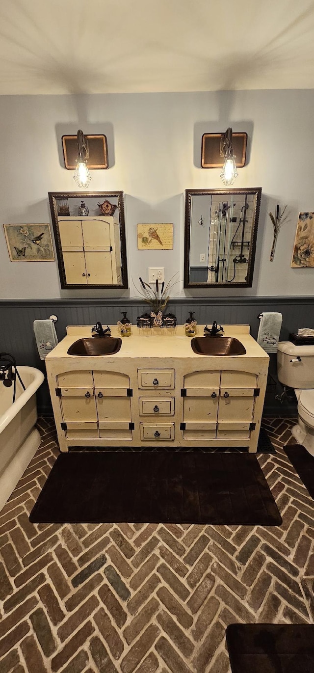 interior space with brick floor, wainscoting, a sink, and toilet