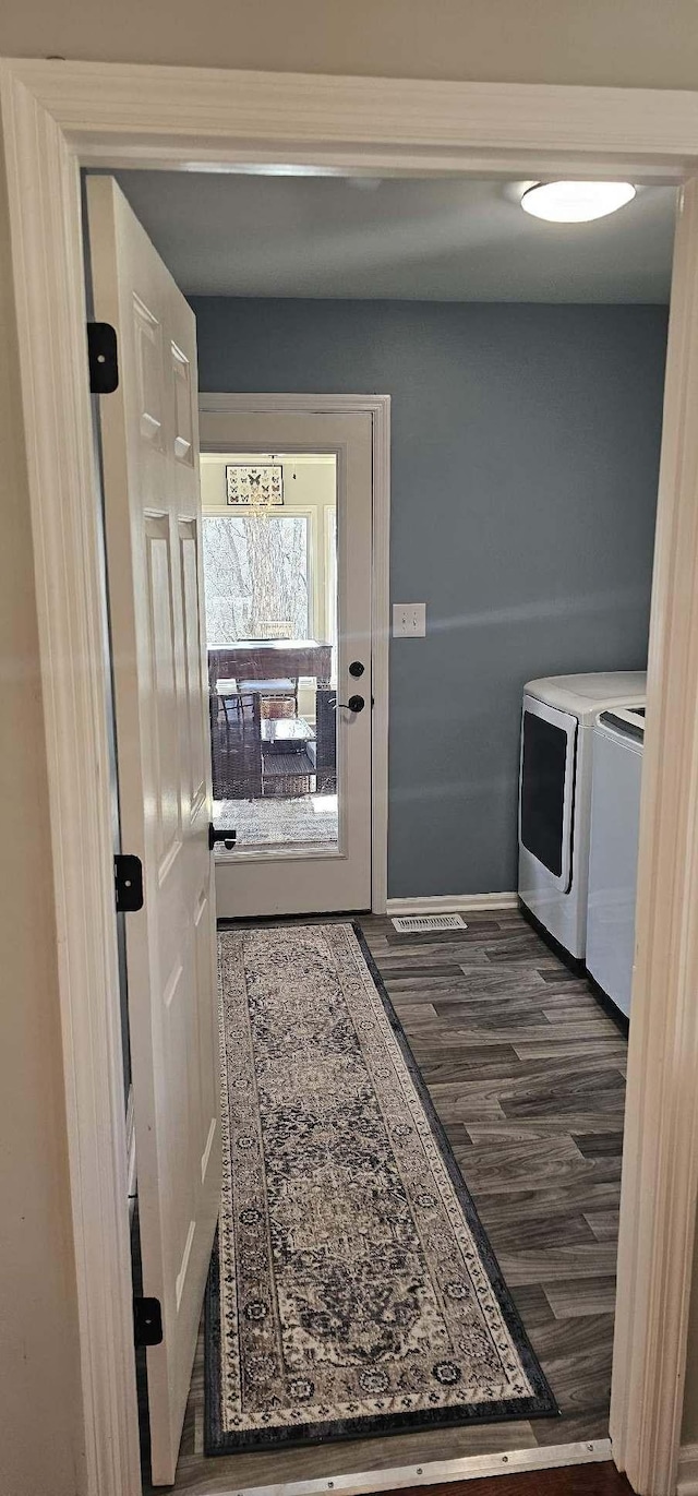 interior space with laundry area, washing machine and dryer, baseboards, and dark wood-style flooring