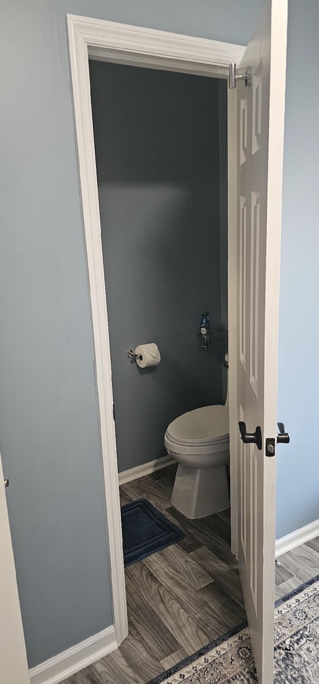 bathroom with wood finished floors, toilet, and baseboards