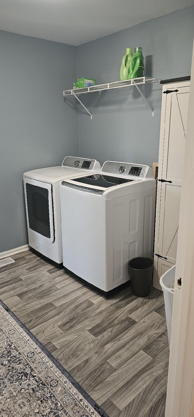 clothes washing area featuring laundry area, wood finished floors, and washing machine and clothes dryer