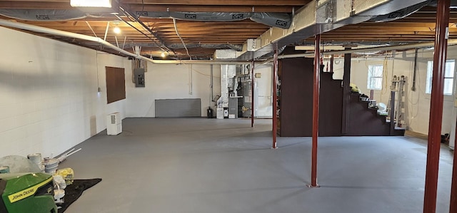 basement featuring electric panel, stairway, and gas water heater