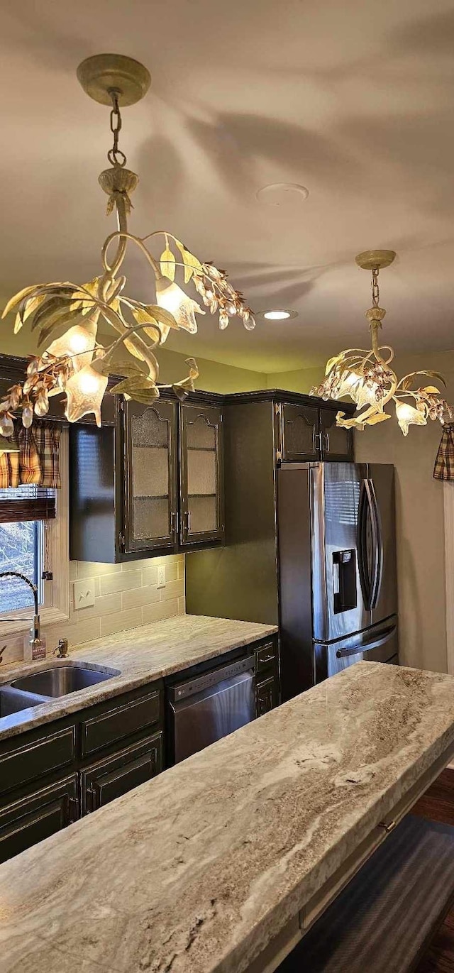 kitchen with stainless steel fridge, tasteful backsplash, dishwashing machine, light stone counters, and a sink