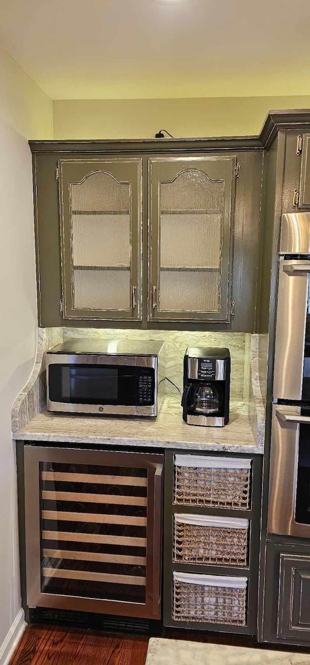 bar featuring wine cooler, appliances with stainless steel finishes, and backsplash