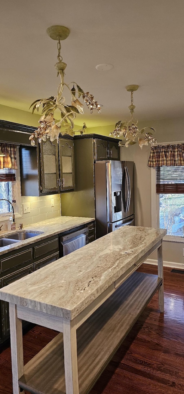 kitchen with decorative light fixtures, dark wood finished floors, backsplash, stainless steel fridge, and dishwashing machine