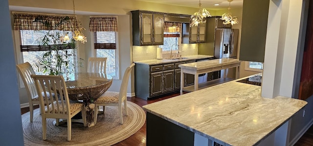 kitchen with dark wood-type flooring, a sink, a notable chandelier, light countertops, and backsplash