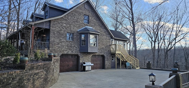 view of property exterior with brick siding, concrete driveway, fence, a garage, and stairs