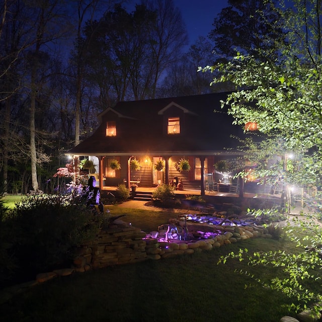 back of house at twilight featuring covered porch
