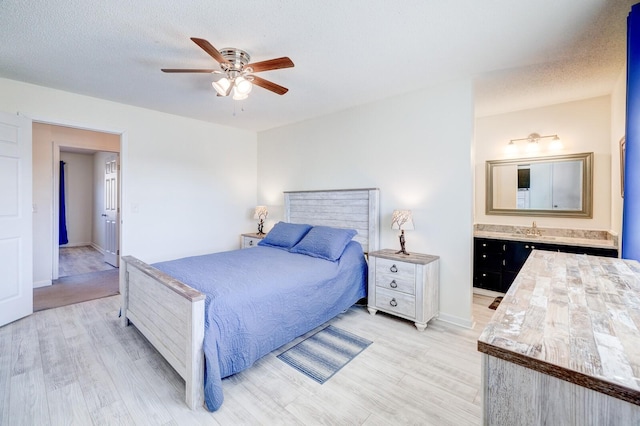 bedroom with sink, a textured ceiling, and light wood-type flooring