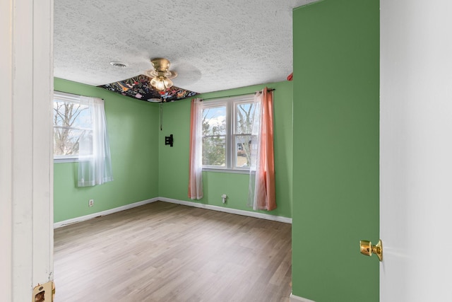 spare room with hardwood / wood-style flooring, a healthy amount of sunlight, and a textured ceiling