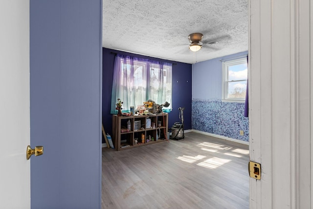 interior space with ceiling fan, wood-type flooring, and a textured ceiling