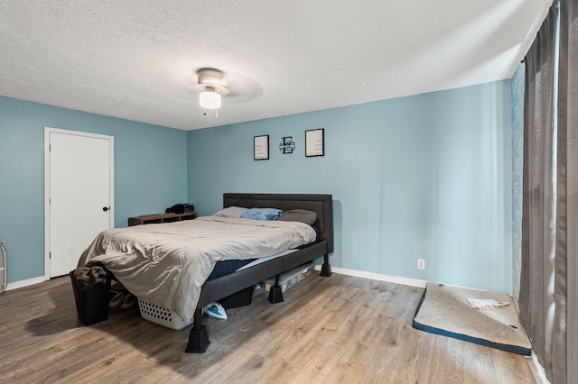 bedroom with ceiling fan, light hardwood / wood-style flooring, and a textured ceiling