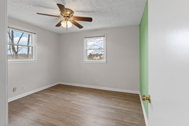 spare room featuring ceiling fan, a healthy amount of sunlight, hardwood / wood-style floors, and a textured ceiling