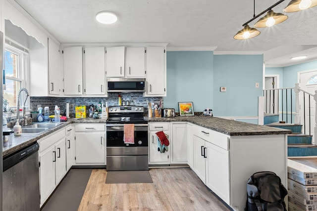 kitchen with sink, appliances with stainless steel finishes, white cabinetry, light hardwood / wood-style floors, and decorative backsplash