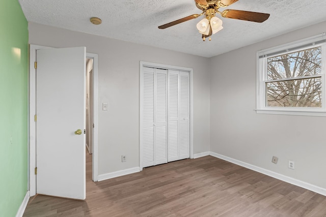 unfurnished bedroom with hardwood / wood-style flooring, ceiling fan, a textured ceiling, and a closet