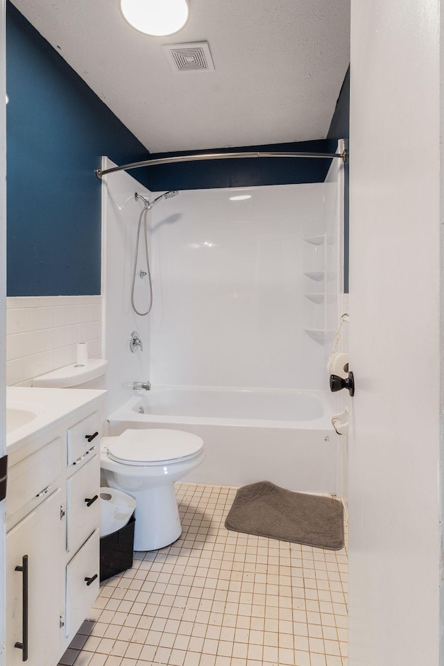 full bathroom with washtub / shower combination, tile patterned flooring, vanity, a textured ceiling, and toilet